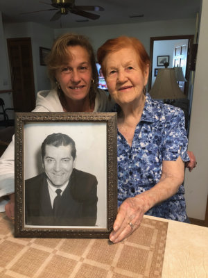 smiling caregiver and old lady with a picture frame of her husband