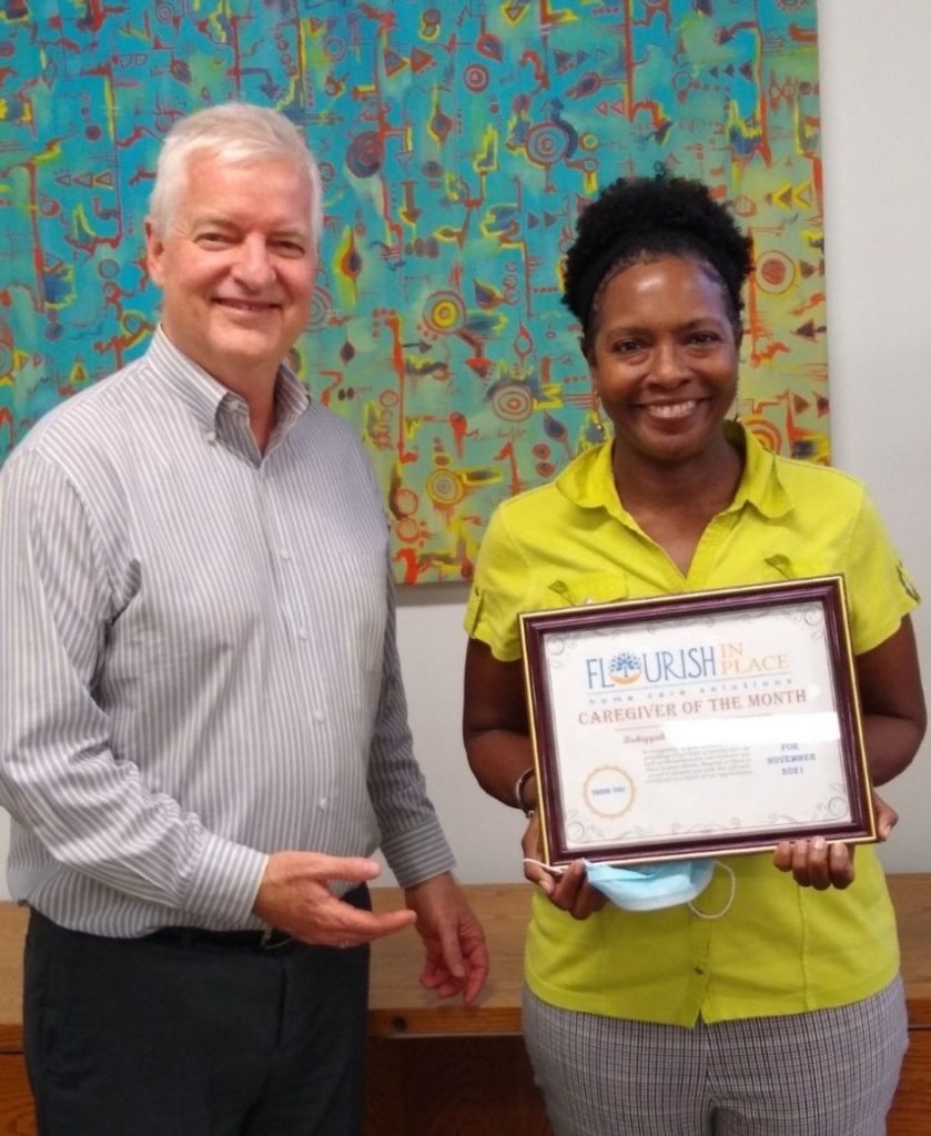 Flourish in Place co-founder, Kim, hands Bahiyyah the caregiver of the month certificate